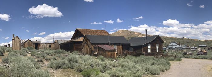 Panoramic view of old houses on field against sky