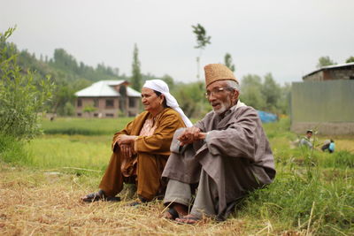 Rear view of people sitting on field