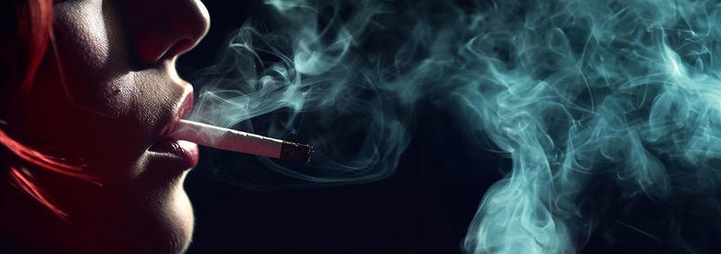 Midsection of woman holding smoke against black background