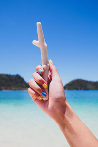 Close-up of hand holding sea against clear blue sky