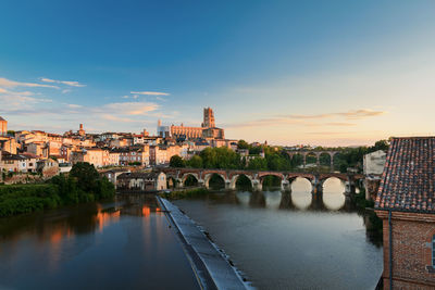 Bridge over river against buildings in city