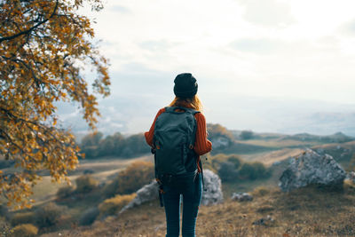 Rear view of man standing on mountain against sky