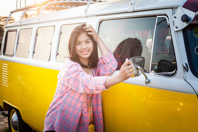 Portrait of women standing with yellow mini van with happiness smile.