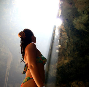 Woman in bikini standing against rock