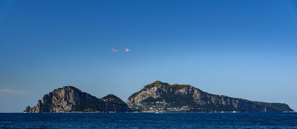 Scenic view of sea and mountains against blue sky