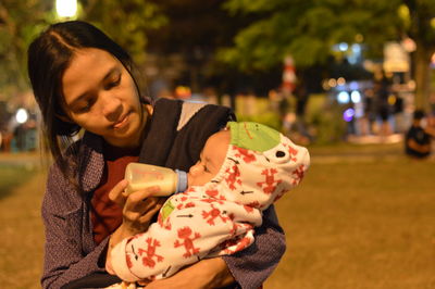 Mother feeding daughter while standing in park