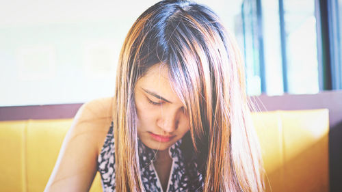 Close-up of beautiful woman looking down while sitting in cafe