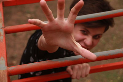 Portrait of teenage boy gesturing while standing behind railing