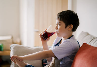 Side view of boy drinking at home