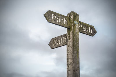 Low angle view of road sign against cloudy sky