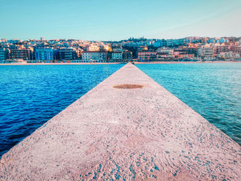 Pier with the sea to the side and the city in front at the sunset