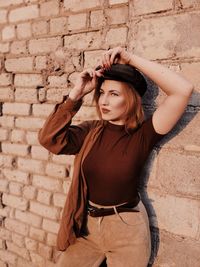 Portrait of woman standing against brick wall