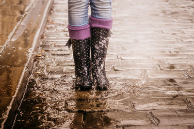 Low section of woman standing in puddle