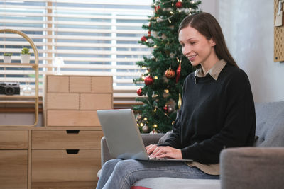 Businesswoman using laptop while sitting on sofa at home