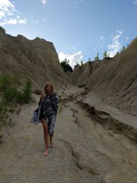 Rear view of woman standing on mountain against sky