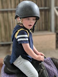 Side view of cute boy sitting on horse