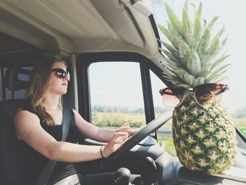 Young woman sitting in car with pineapple