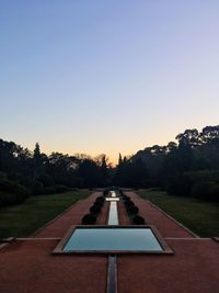 Footpath in park against clear sky during sunset