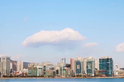 Sea by cityscape against sky