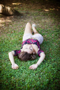 High angle view of teenage girl lying on grassy field in park