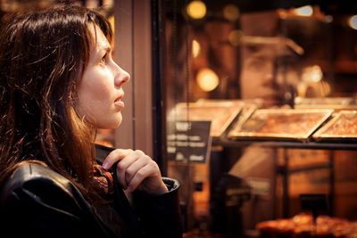 Attractive woman in a black jacket stands near the shop window