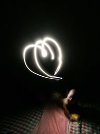 Blurred image of person holding heart shape at night