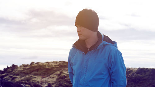 Man looking away while standing against sky