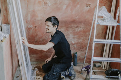 Caucasian man washes window frame with sponge.