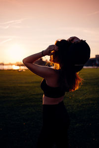 Full length of woman standing on field against sky during sunset