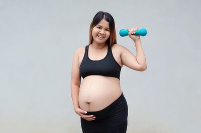 Smiling young woman standing against the wall
