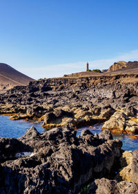 Scenic view of rocks against clear blue sky