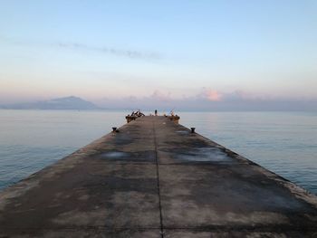 Pier over sea against sky during sunset