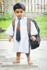 Full length of boy in school uniform standing on footpath