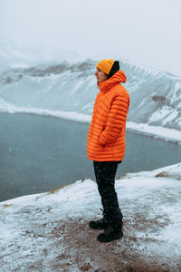 Rear view of person standing on snow covered shore