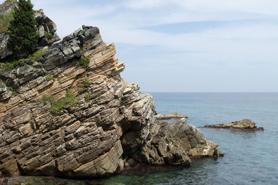 Rock formation by sea against sky