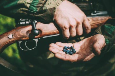 Midsection of army solider holding berries while standing outdoors