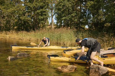 Men at lake pushing kayaks on water