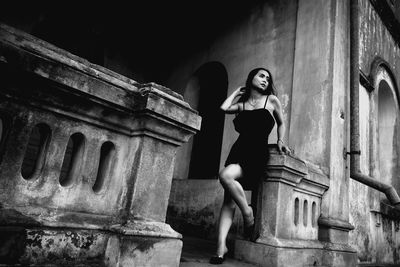 Full length of beautiful woman leaning on old building