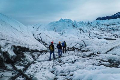 People on snowcapped mountains against sky