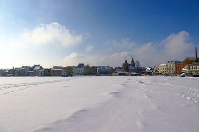 Houses on snowcapped landscape against blue sky