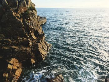 Rock formation in sea against clear sky