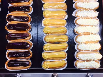 Directly above shot of various eclairs for sale at in bakery