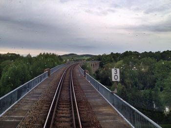 Railroad track against cloudy sky