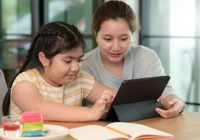 Asian girl studying privately with tutor at home, siblings teaching homework, online learning.