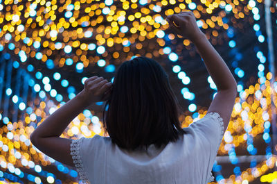 Rear view of woman against illuminated lights 