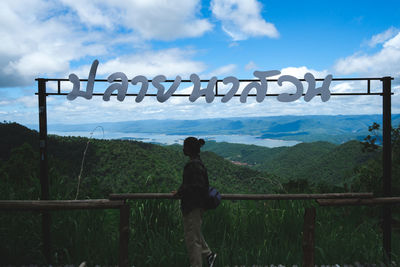 Rear view of woman standing by railing against sky