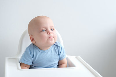 Portrait of cute baby boy sitting on bed at home