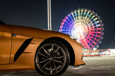 Ferris wheel in illuminated city against sky at night