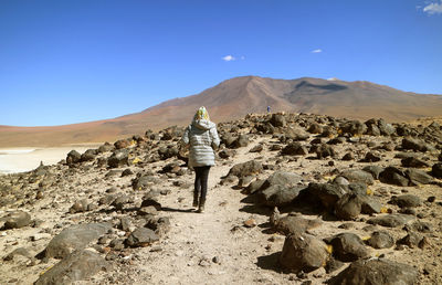 Rear view of man on rock against sky