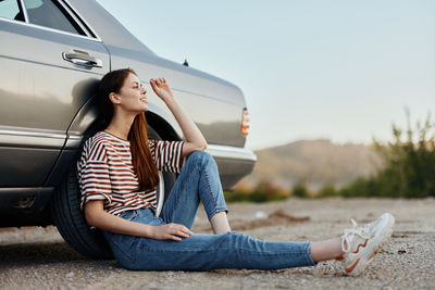 Young woman sitting on car